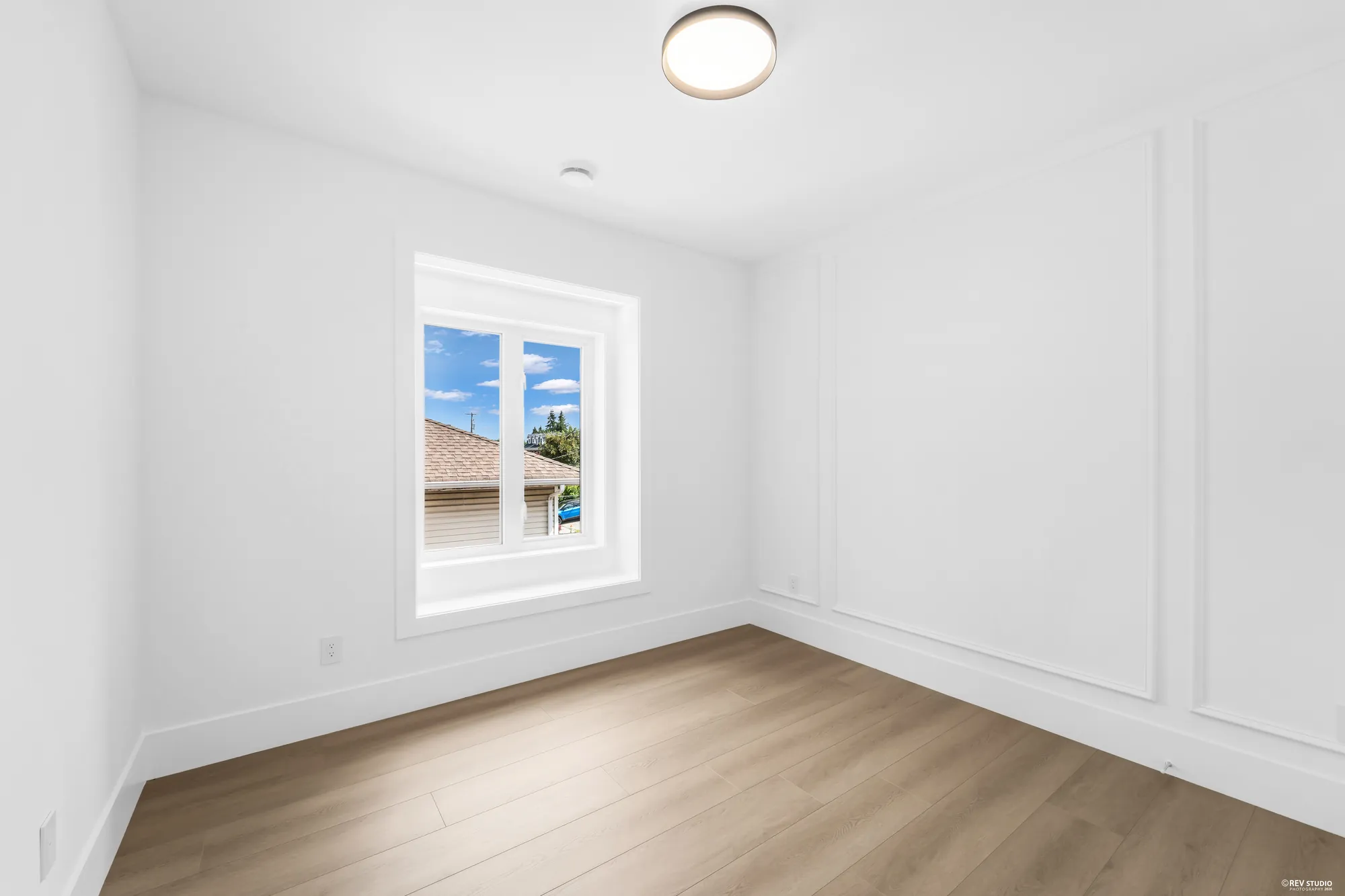 An unfurnished bedroom with panelled walls and one window