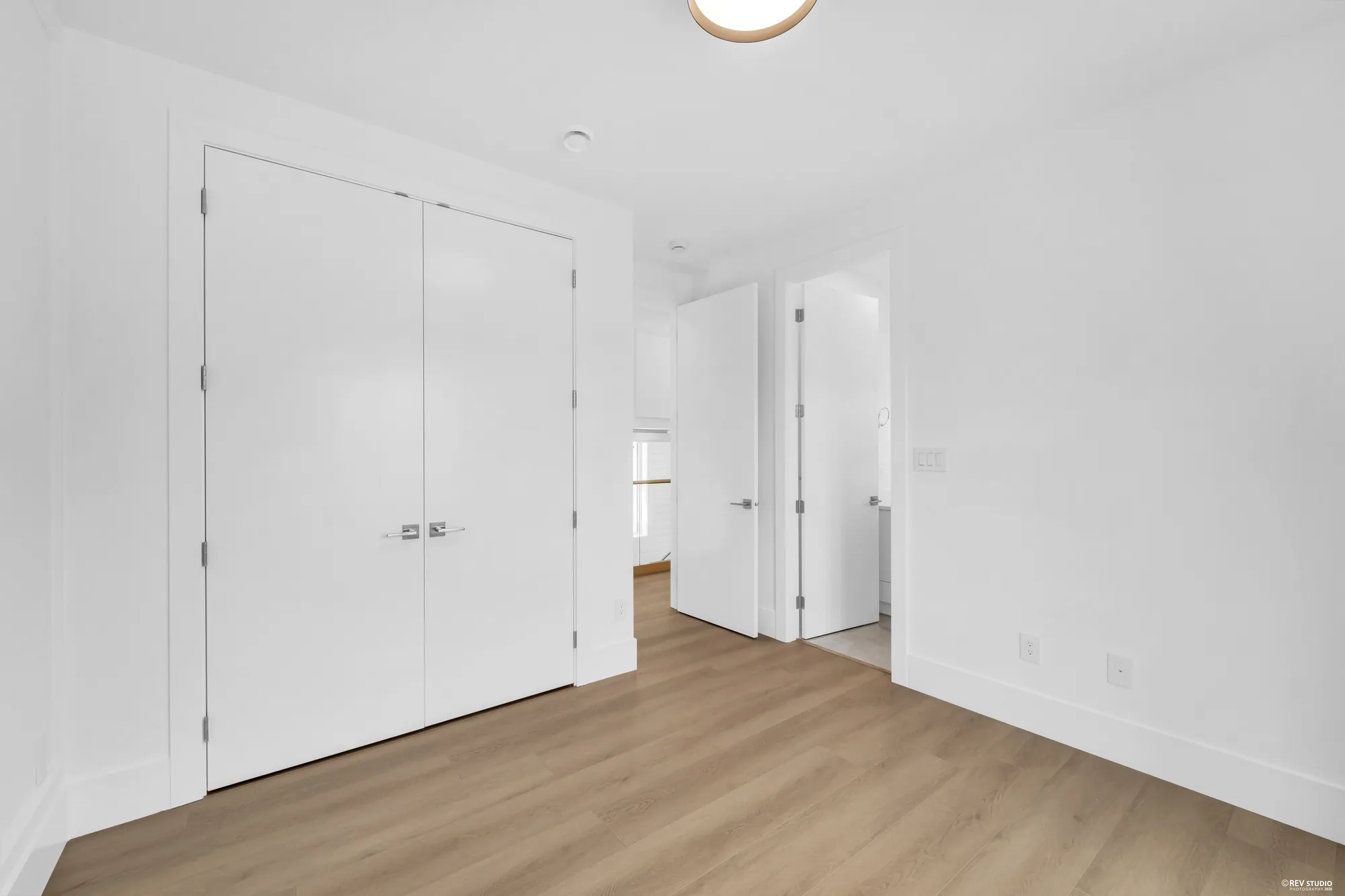 An unfurnished bedroom showing the closet doors and the door to the landing