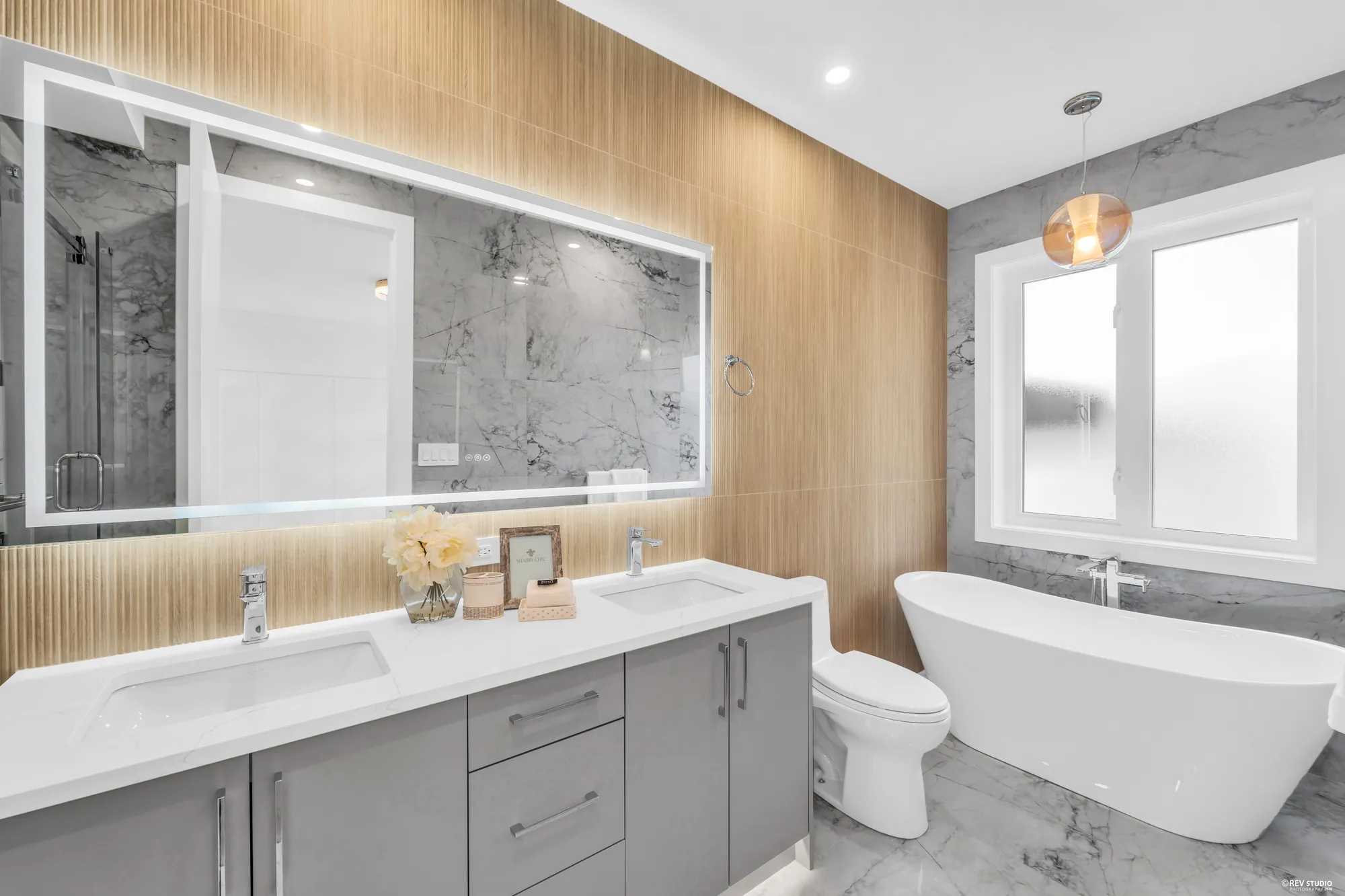 A long bathroom with a double vanity down one side and a free-standing tub at the end