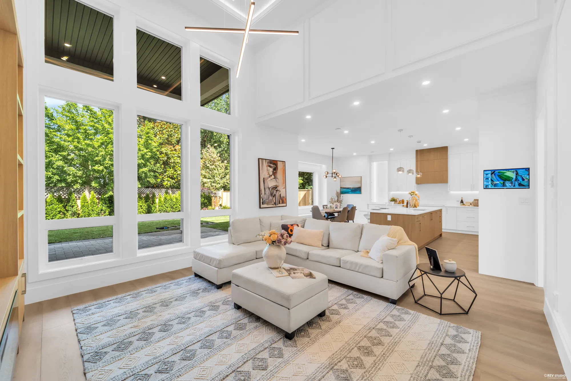 The family room with a wall of glass to the garden and the kitchen open beyond the sofa