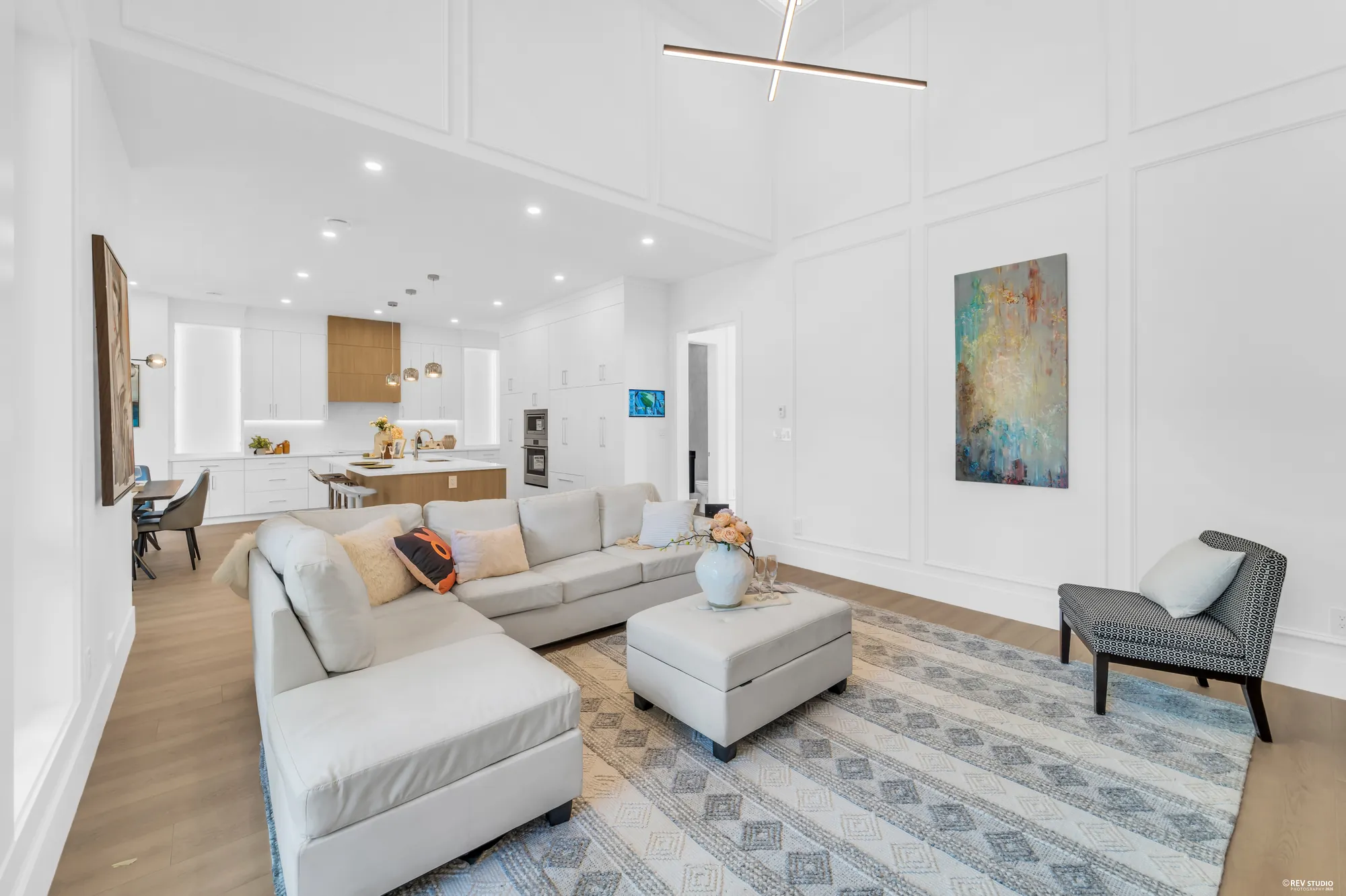Wide view across the seating to the kitchen island and the tall windows