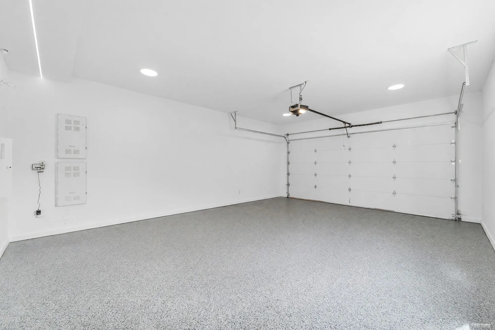 The empty double garage, epoxy floor, opener rail overhead