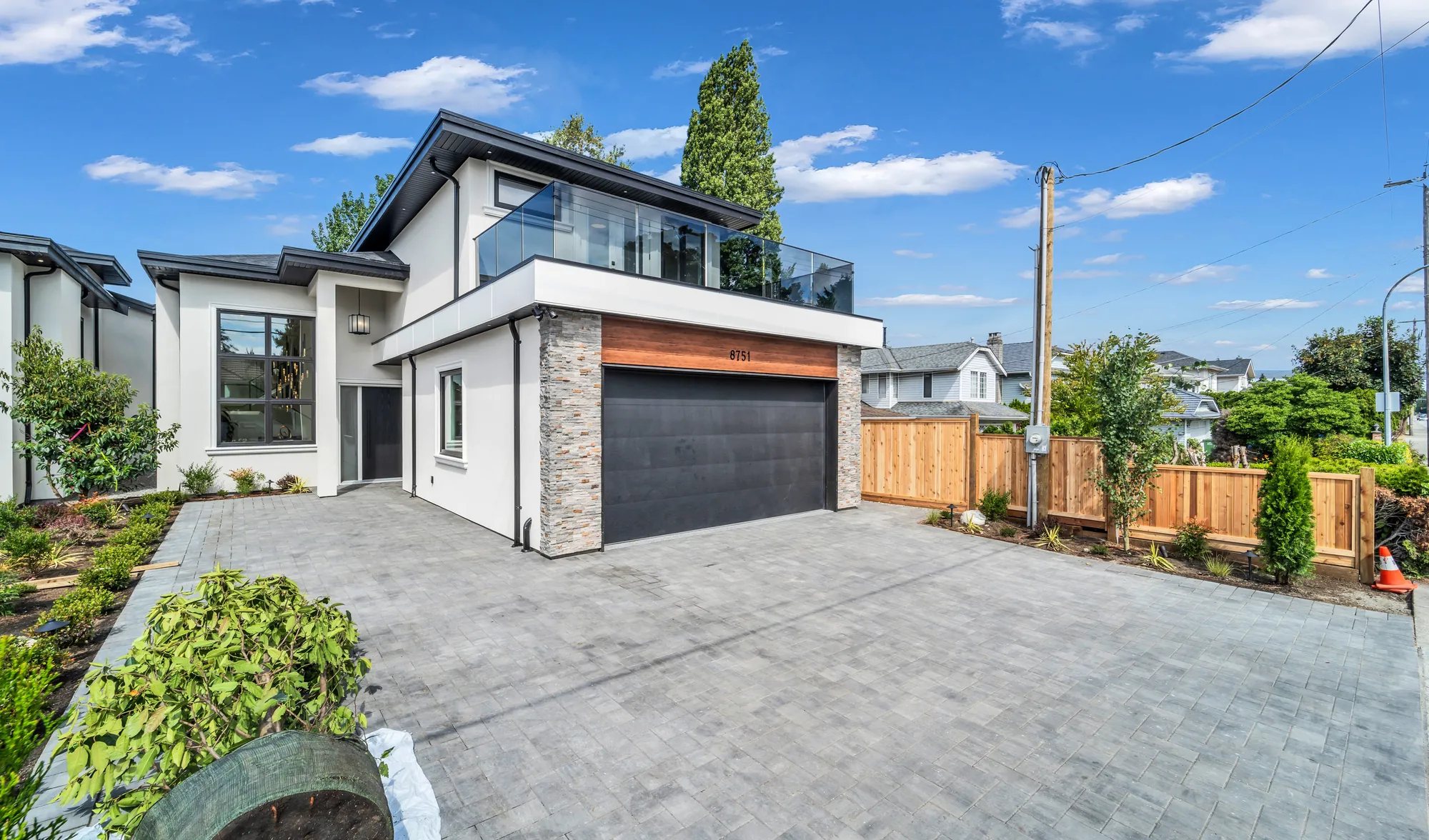 8751 No. 2 Road from the driveway: stacked stone, a cedar header over the garage and a glass-railed deck above