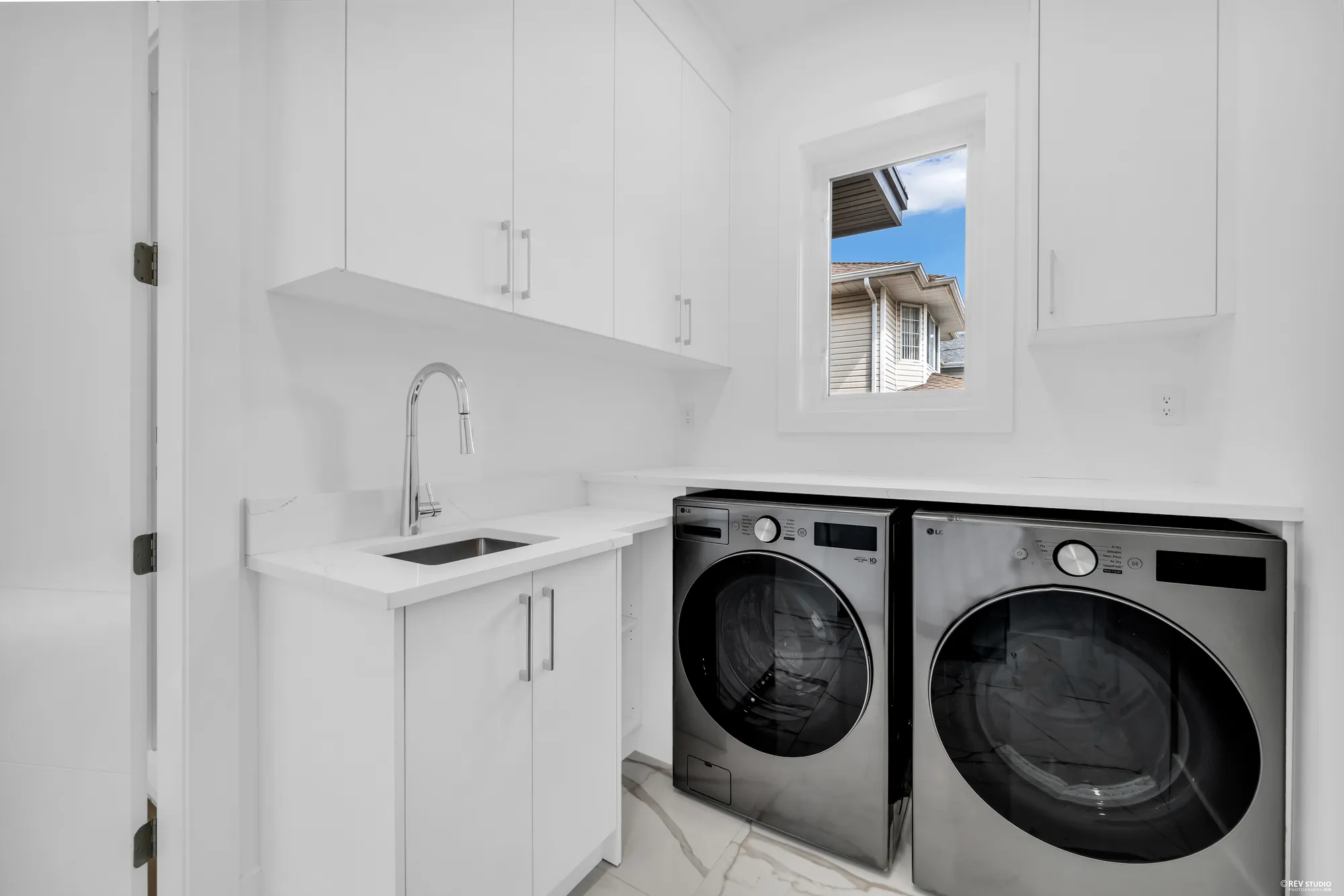 The family laundry room with a sink, counter, wall cabinets and a full-size washer and dryer