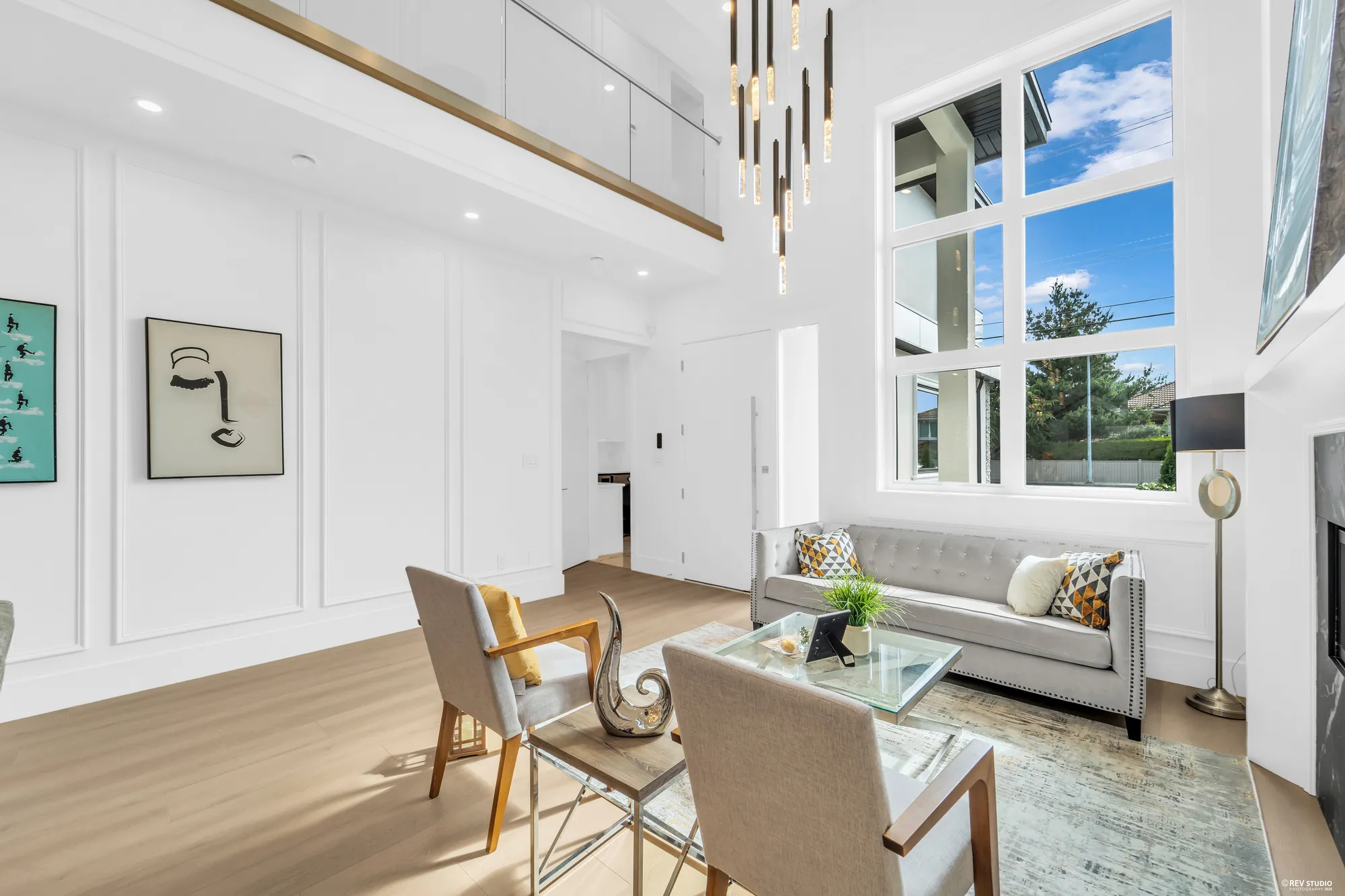 Seating around the fireplace with a stone surround, tall window to the right