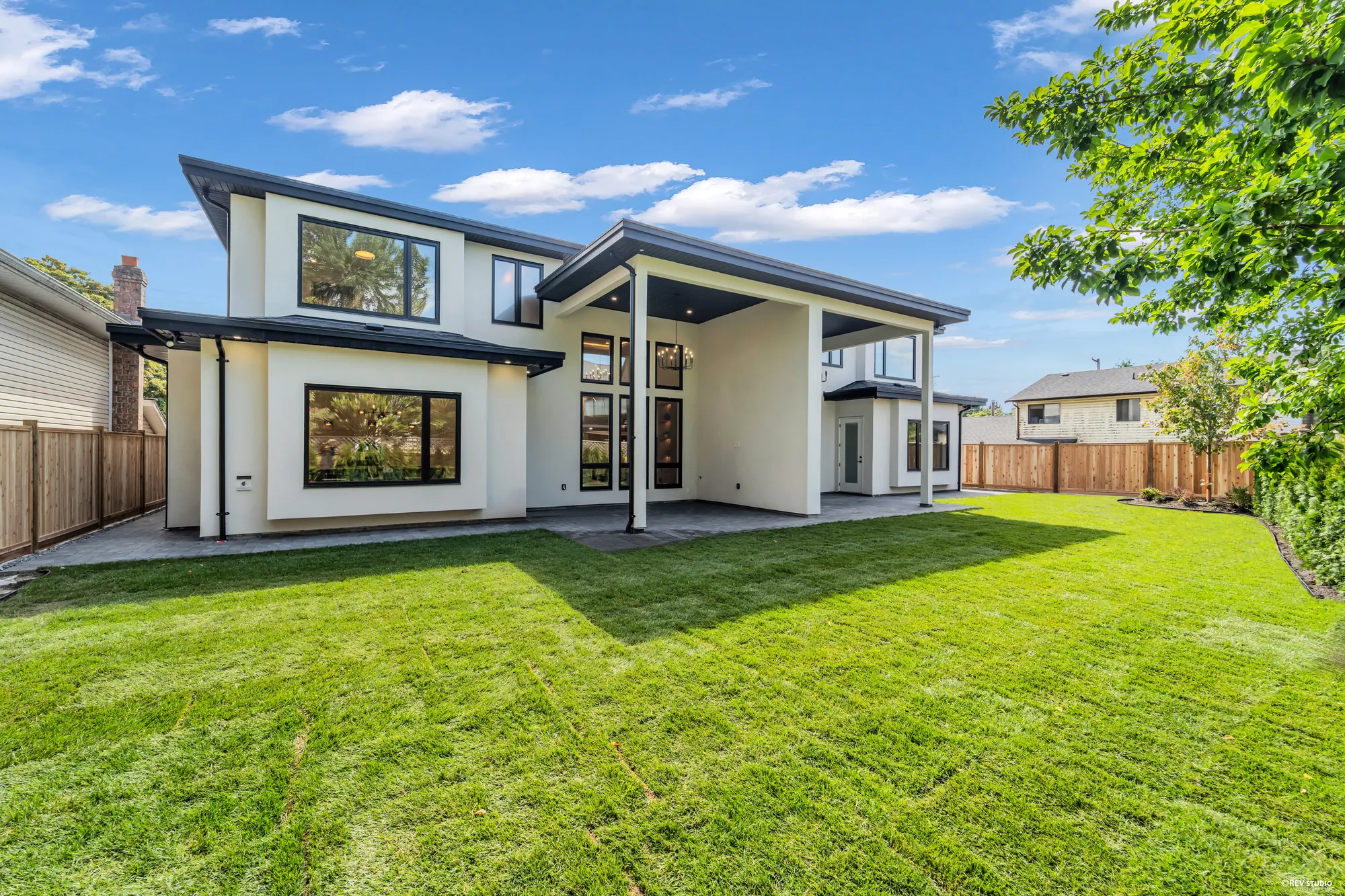 The back of the house across the lawn, covered patio under the deep roof