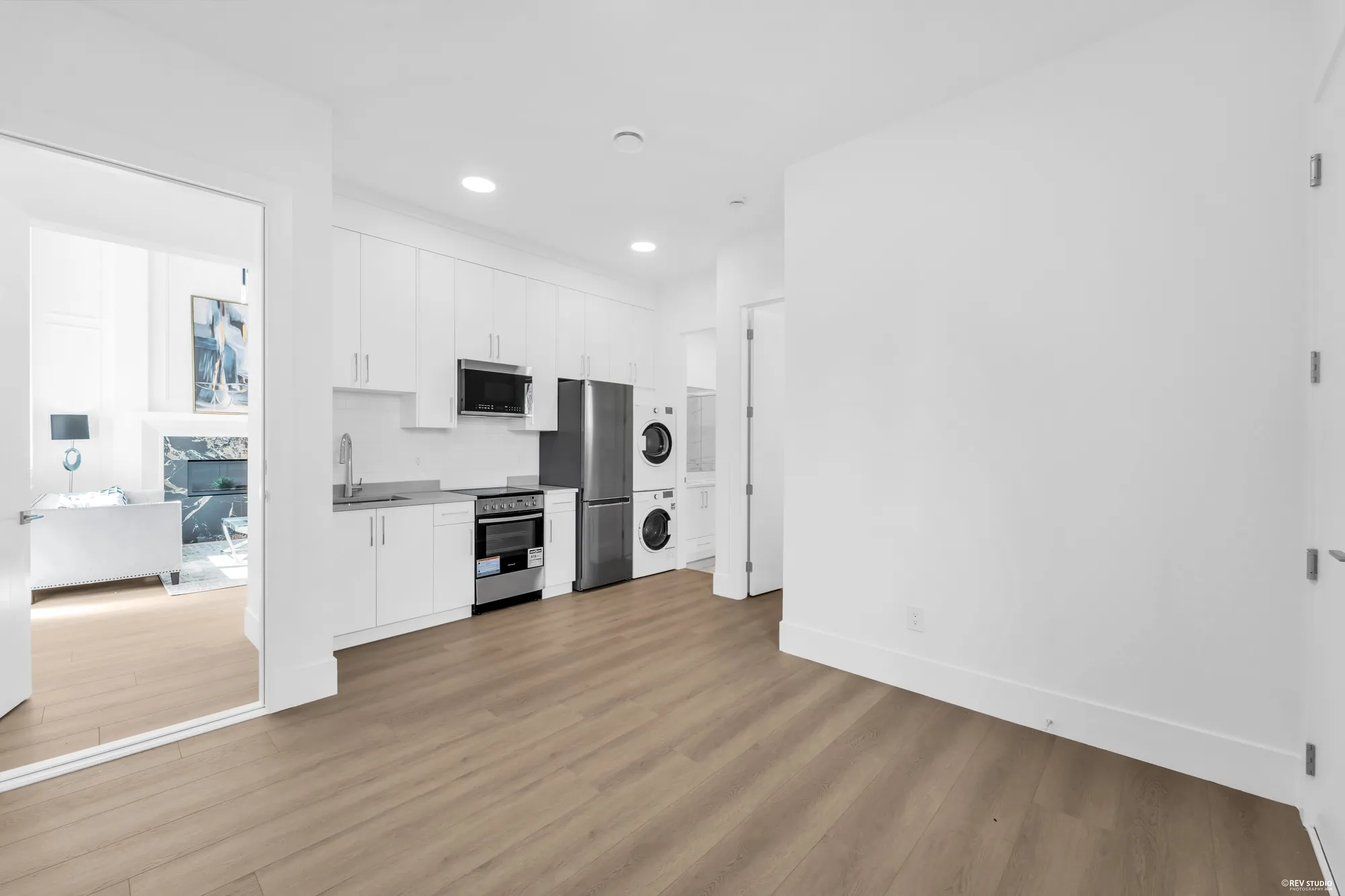 The suite kitchen with a range, fridge and a stacked washer and dryer, sitting area beyond